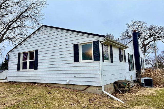 view of side of home featuring metal roof, a chimney, and cooling unit