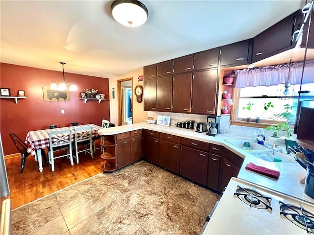 kitchen featuring decorative light fixtures, a notable chandelier, light countertops, dark brown cabinetry, and a peninsula