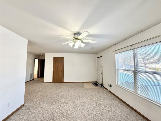 empty room with light colored carpet, ceiling fan, visible vents, and baseboards