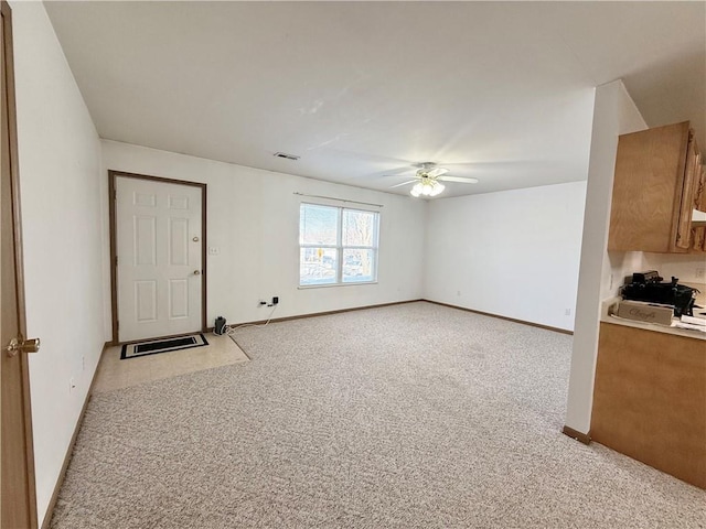 interior space featuring ceiling fan, baseboards, visible vents, and light colored carpet