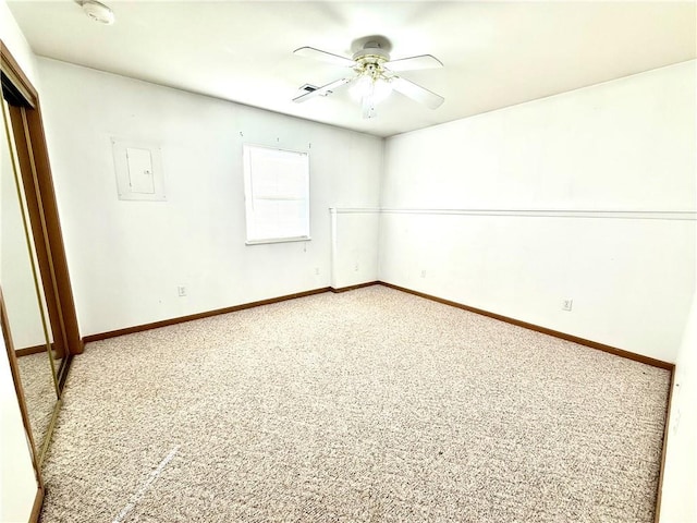 unfurnished room featuring light carpet, electric panel, a ceiling fan, and baseboards