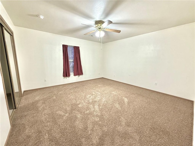 carpeted spare room with a ceiling fan