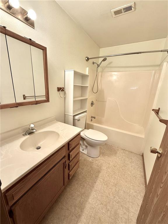 bathroom with shower / washtub combination, visible vents, toilet, vanity, and tile patterned floors