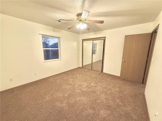 unfurnished bedroom featuring carpet floors, a closet, visible vents, and a ceiling fan