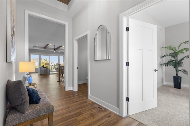 corridor featuring wood finished floors, visible vents, and baseboards