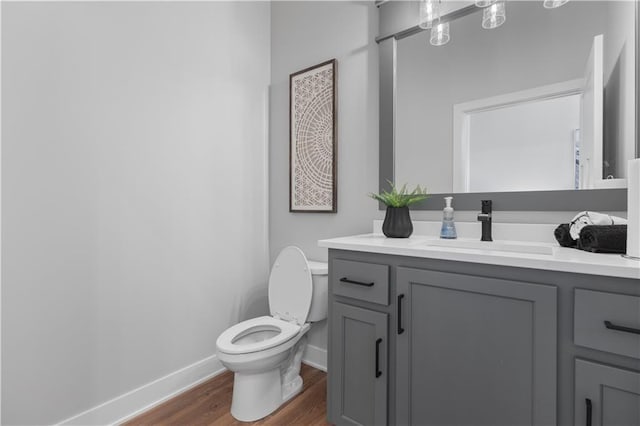 bathroom with baseboards, toilet, wood finished floors, and vanity