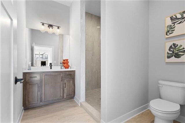 bathroom featuring a walk in shower, toilet, vanity, and baseboards