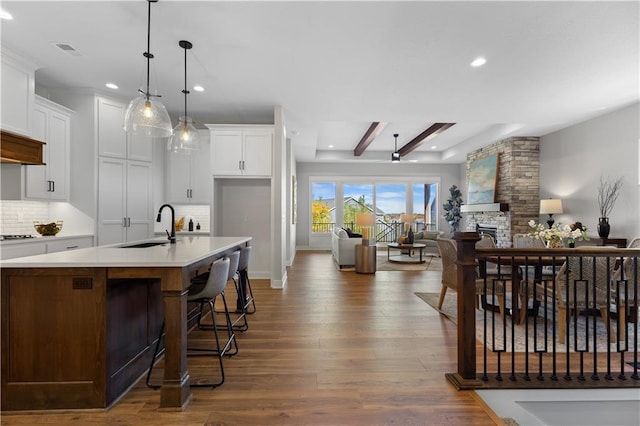 kitchen with wood finished floors, a fireplace, a sink, decorative backsplash, and open floor plan