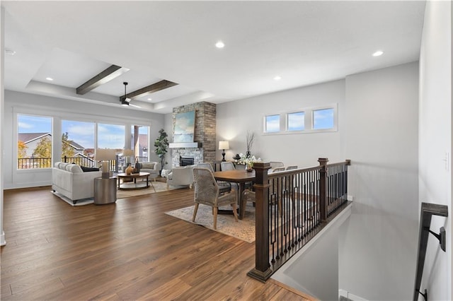 dining space featuring dark wood finished floors, beam ceiling, recessed lighting, a fireplace, and ceiling fan