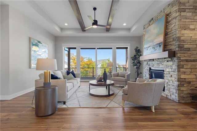 living room featuring beamed ceiling, baseboards, wood finished floors, and a fireplace