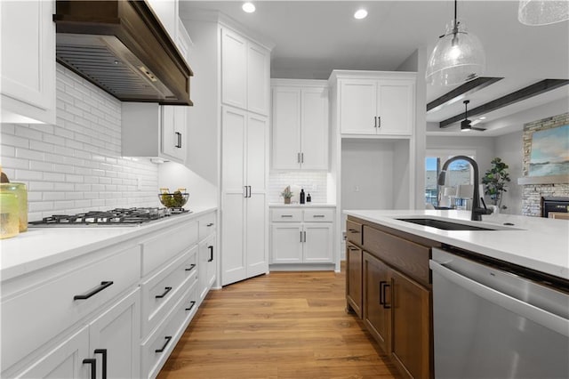 kitchen featuring light countertops, stainless steel appliances, custom exhaust hood, white cabinetry, and a sink