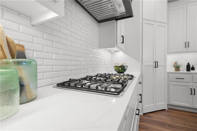 kitchen featuring tasteful backsplash, dark wood-style floors, range hood, white cabinets, and stainless steel gas cooktop