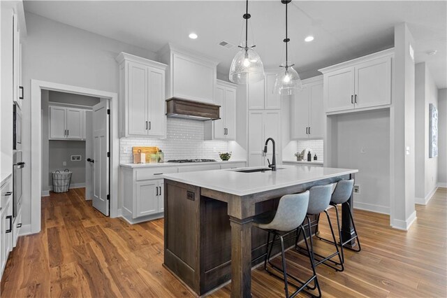 kitchen featuring premium range hood, a sink, gas stovetop, light countertops, and stainless steel oven