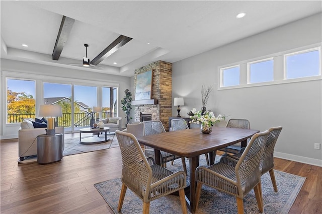 dining area with a stone fireplace, a healthy amount of sunlight, baseboards, and wood finished floors