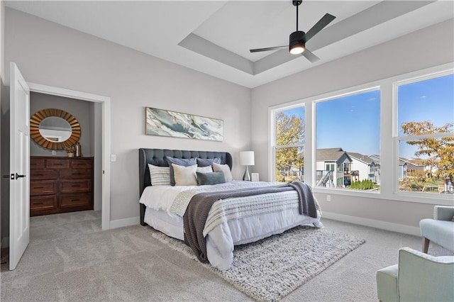 carpeted bedroom with a tray ceiling, baseboards, and ceiling fan