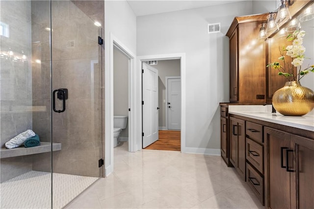 bathroom with visible vents, toilet, a stall shower, double vanity, and baseboards