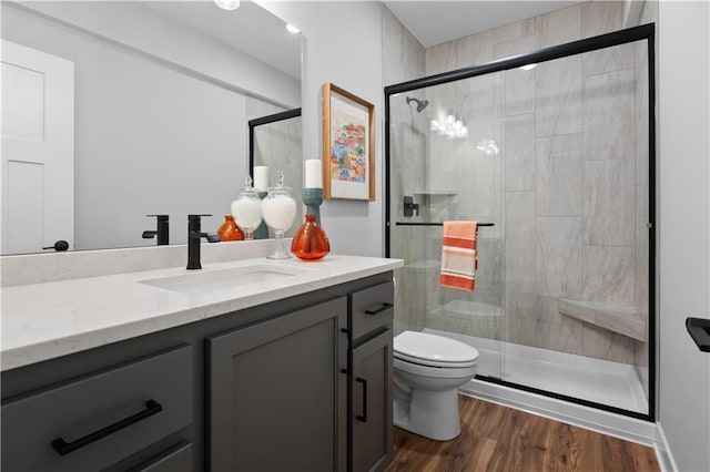 bathroom with vanity, a shower stall, toilet, and wood finished floors