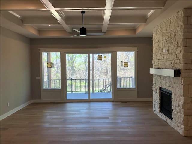 unfurnished living room featuring baseboards, beam ceiling, a fireplace, and ceiling fan