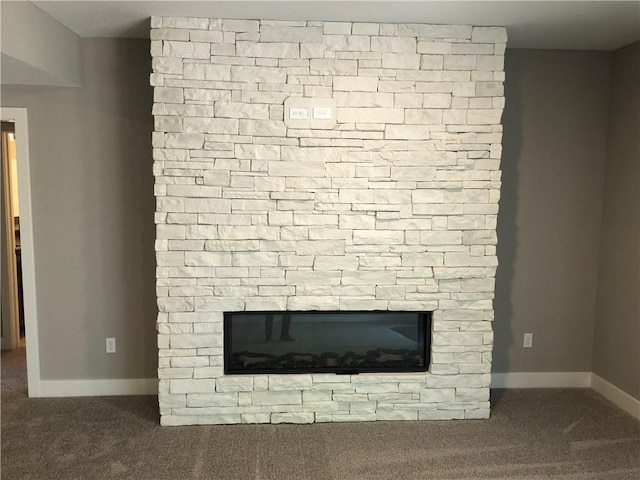 room details featuring baseboards, a stone fireplace, and carpet flooring