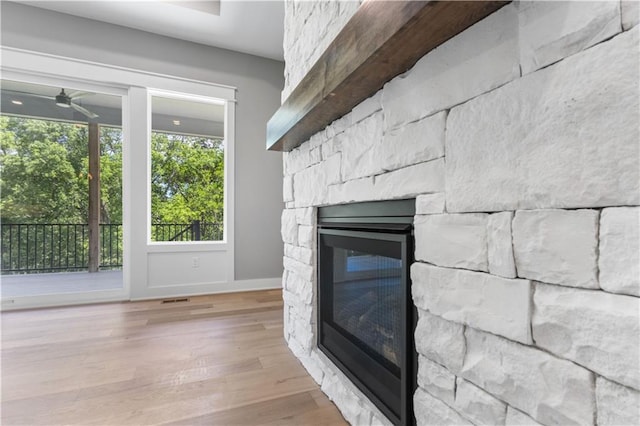 17147 S Heatherwood St, Olathe, KS 66062 - detailed view of a stone fireplace, ceiling fan, wood finished floors, and baseboards
