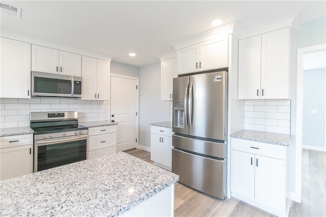 kitchen with light wood-type flooring, white cabinets, and stainless steel appliances