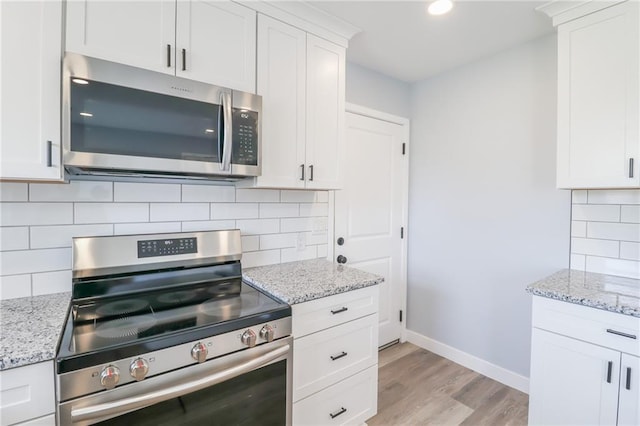 kitchen with stainless steel appliances, white cabinets, baseboards, light wood-type flooring, and light stone countertops