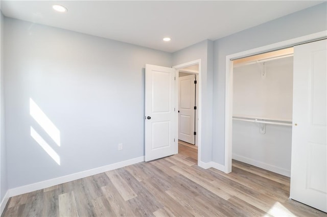 unfurnished bedroom featuring a closet, baseboards, wood finished floors, and recessed lighting