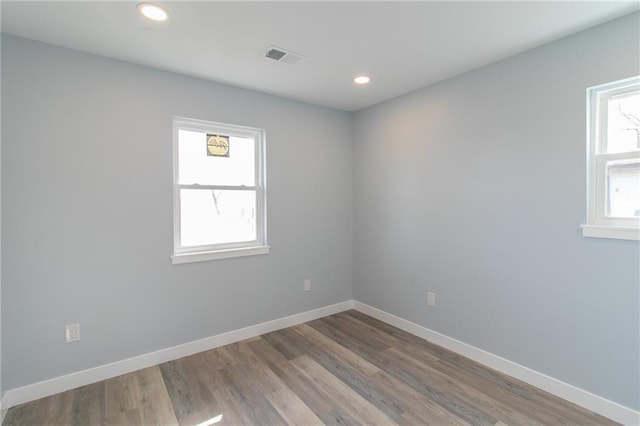 empty room featuring visible vents, baseboards, wood finished floors, and recessed lighting