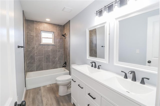 full bathroom featuring double vanity, a sink, toilet, and wood finished floors