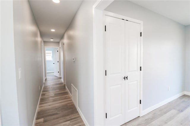 hall featuring light wood-type flooring, visible vents, baseboards, and recessed lighting