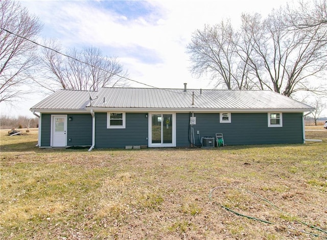 rear view of house with a yard, metal roof, and central AC unit