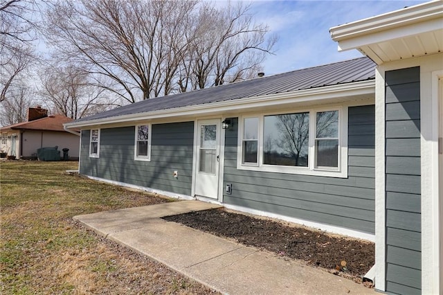 property entrance featuring metal roof and a lawn