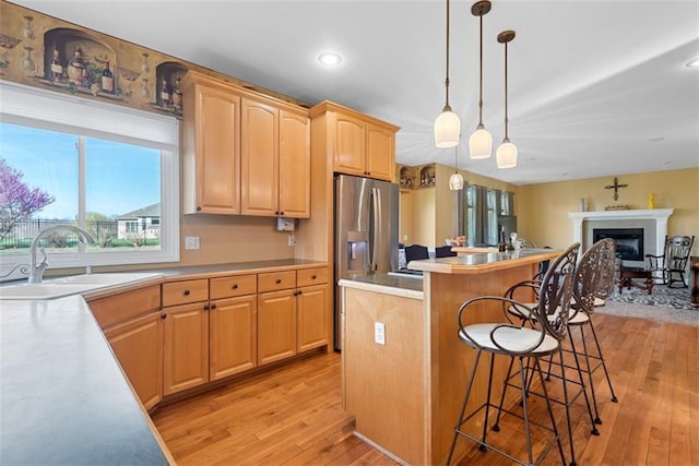 15498 Cedar Ln, Basehor, KS 66007 - kitchen with a kitchen breakfast bar, light wood-type flooring, stainless steel fridge, a fireplace, and light countertops