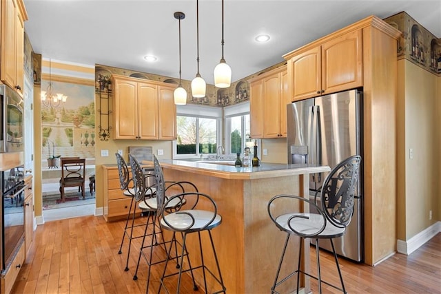 15498 Cedar Ln, Basehor, KS 66007 - kitchen featuring stainless steel appliances, a breakfast bar area, light wood-style floors, light brown cabinets, and recessed lighting