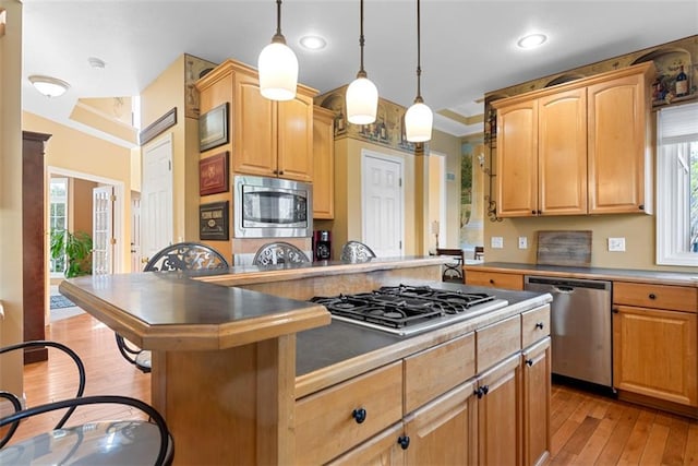 15498 Cedar Ln, Basehor, KS 66007 - kitchen featuring appliances with stainless steel finishes, crown molding, light wood-type flooring, a kitchen bar, and hanging light fixtures