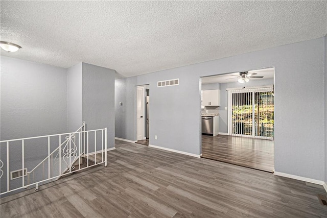 spare room with a ceiling fan, wood finished floors, visible vents, and baseboards