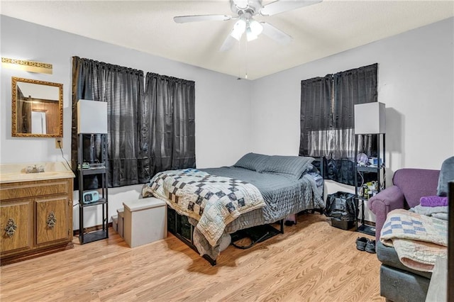 bedroom with ceiling fan, light wood-style flooring, and a sink