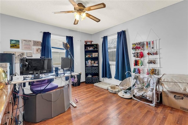 home office featuring a textured ceiling, ceiling fan, wood finished floors, and a wealth of natural light