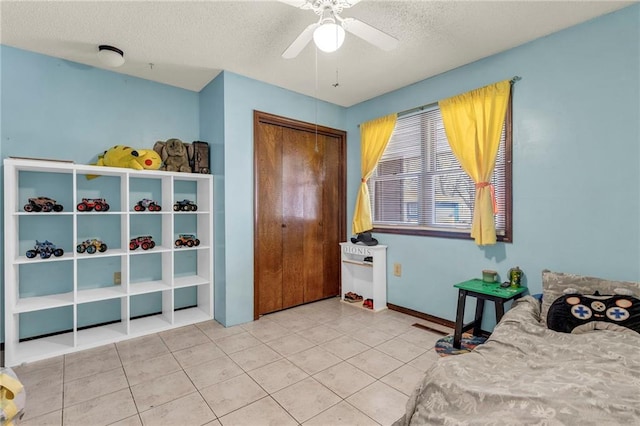 bedroom with a ceiling fan, tile patterned flooring, a closet, and a textured ceiling