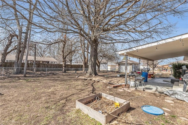 view of yard featuring fence, a vegetable garden, a patio, and an outbuilding