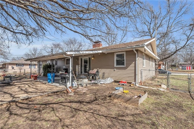 back of house featuring a garden, a patio, a chimney, a gate, and fence