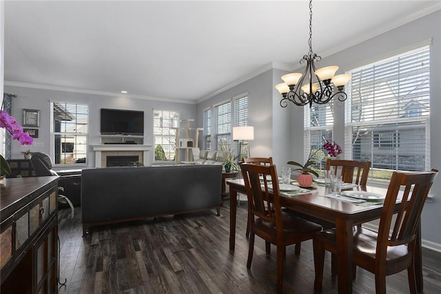 dining area featuring a tile fireplace, crown molding, an inviting chandelier, and dark wood-style flooring