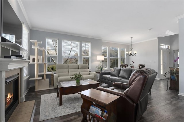 living room with dark wood finished floors, a tile fireplace, crown molding, and an inviting chandelier