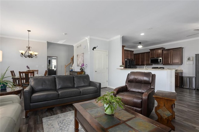 living area featuring stairway, dark wood-type flooring, a chandelier, and crown molding