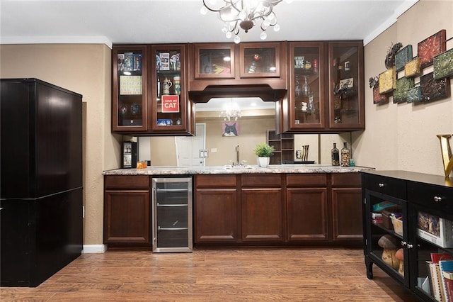 bar with ornamental molding, wood finished floors, freestanding refrigerator, wine cooler, and wet bar