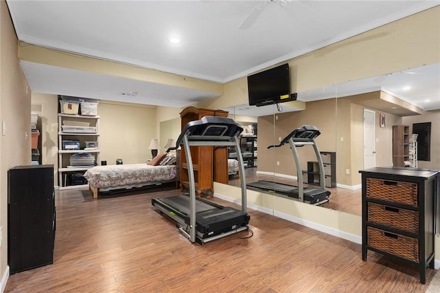 exercise area with a ceiling fan, crown molding, wood finished floors, and baseboards