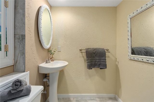 bathroom with a sink, baseboards, and a textured wall