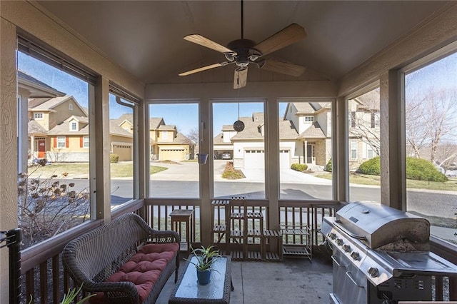 sunroom / solarium with a residential view, a ceiling fan, and vaulted ceiling