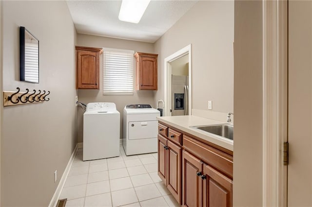 laundry area with baseboards, light tile patterned floors, cabinet space, independent washer and dryer, and a sink