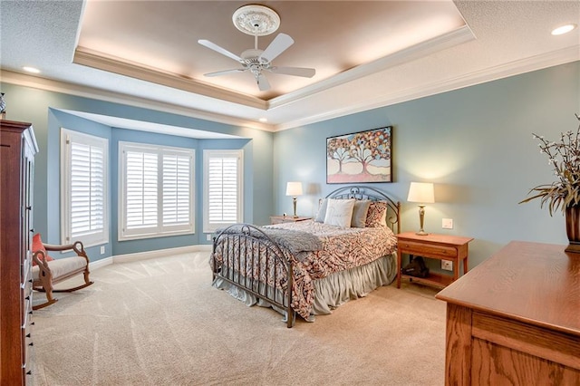 carpeted bedroom with baseboards, a ceiling fan, a tray ceiling, and ornamental molding